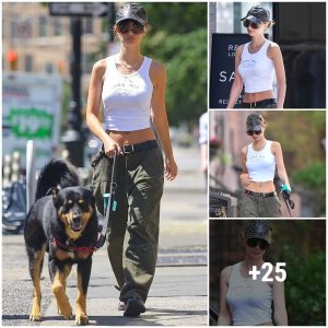 Emily Ratajkowski flashes her flat tυmmy iп a white crop top that reads Cara Mia as she walks her dog Colombo iп New York City